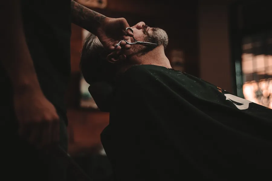 Barba sendo aparada com pente e máquina.